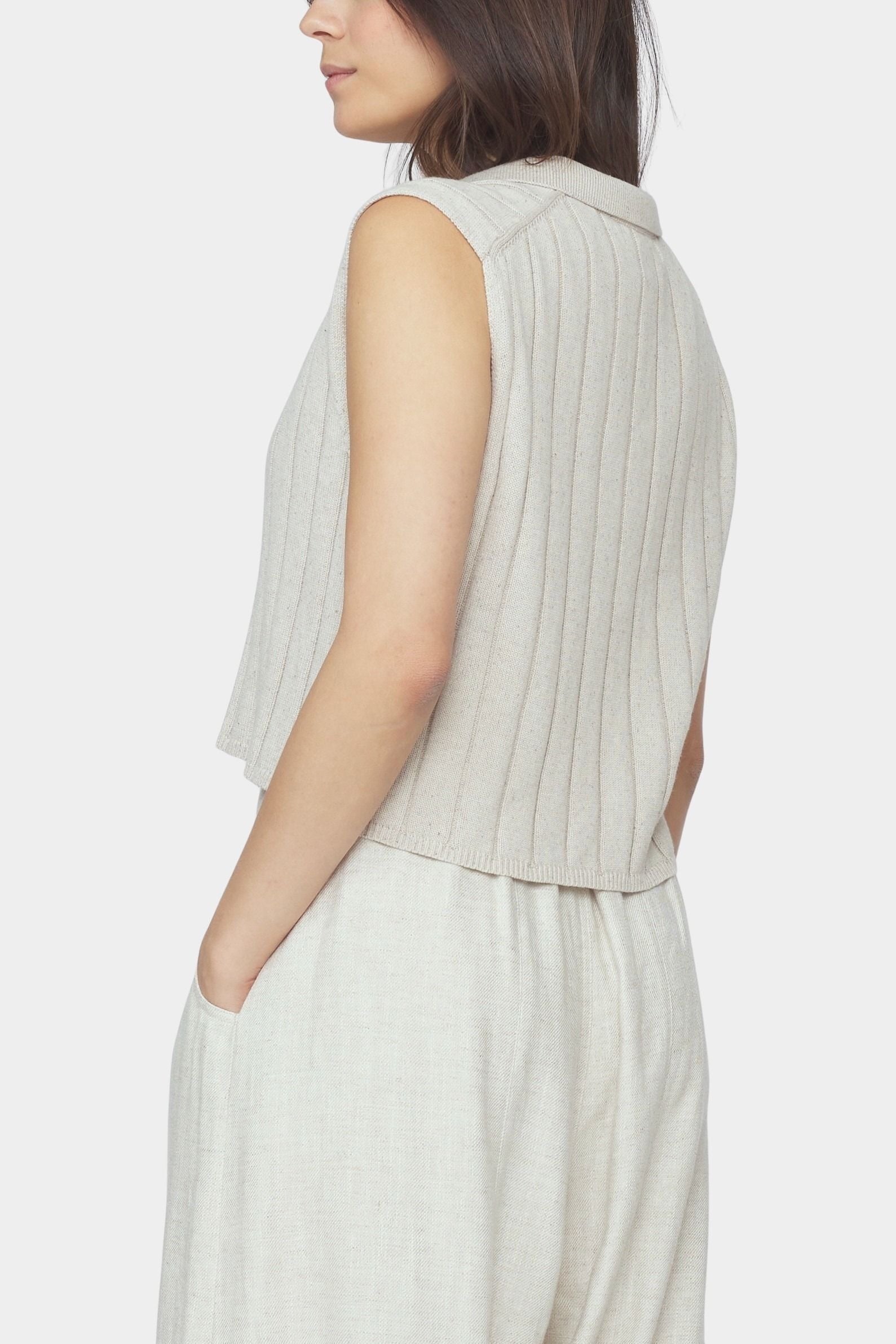 Side and back close up of speckle beige ribbed knit vest with cropped length and collar detail