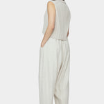 Back and side view of speckle beige sleeveless ribbed knit vest with collar and cropped hem styled with relaxed light beige pants