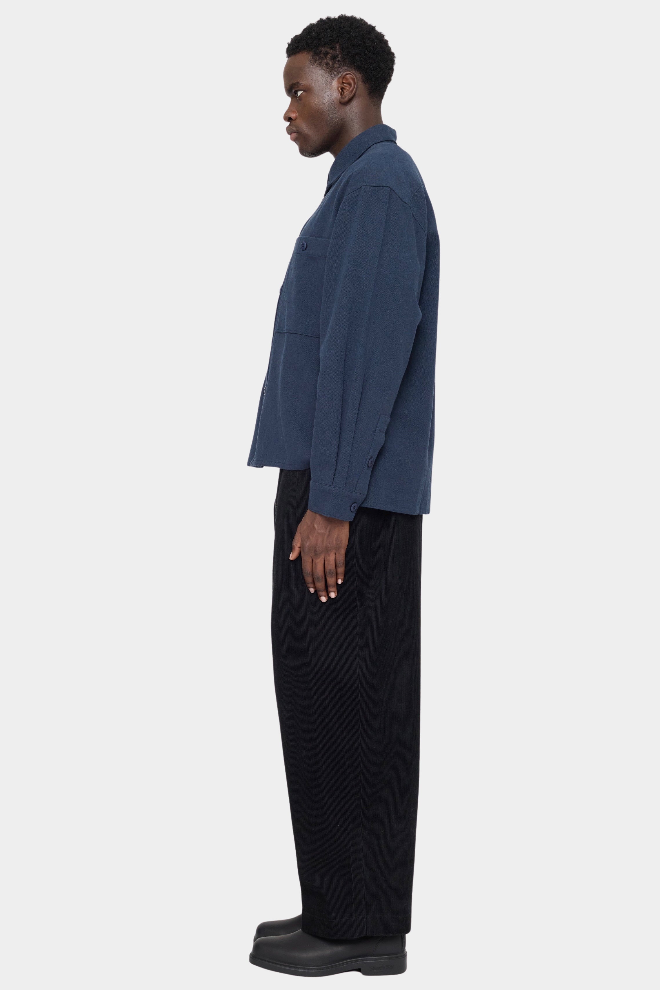 Side view of the navy Relaxed Pocket Shirt showing its boxy shape and buttoned cuff