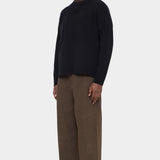 Angled front view of the black merino sweater showing its contrast patch pocket and button placket