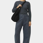 Front view of the black cotton commuter bag worn close to the body with its wide strap across the shoulder