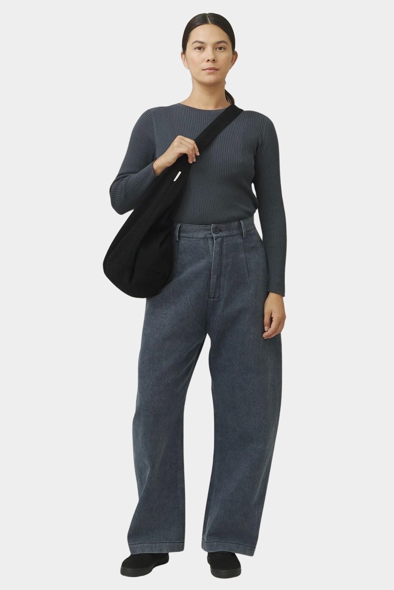 Front view of the black cotton commuter bag worn close to the body with its wide strap across the shoulder