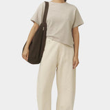 Model carrying the Taupe Brown cotton commuter bag on one shoulder, showing its deep rounded body and wide strap at YUCCA Denver
