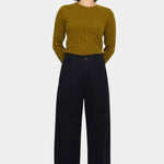 Black straight legged trouser styled with an olive ribbed sweater, showing the clean front waistband