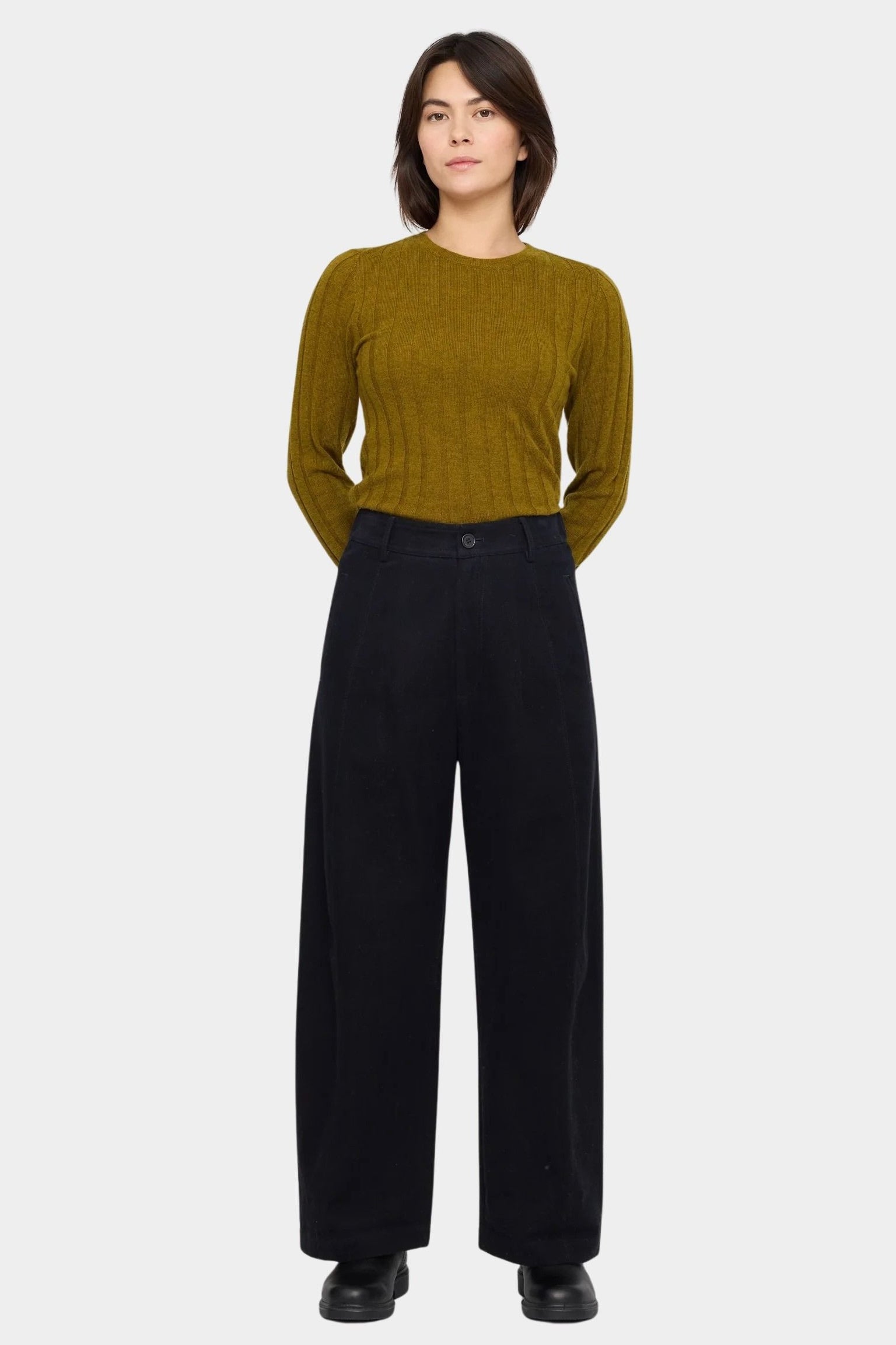 Black straight legged trouser styled with an olive ribbed sweater, showing the clean front waistband