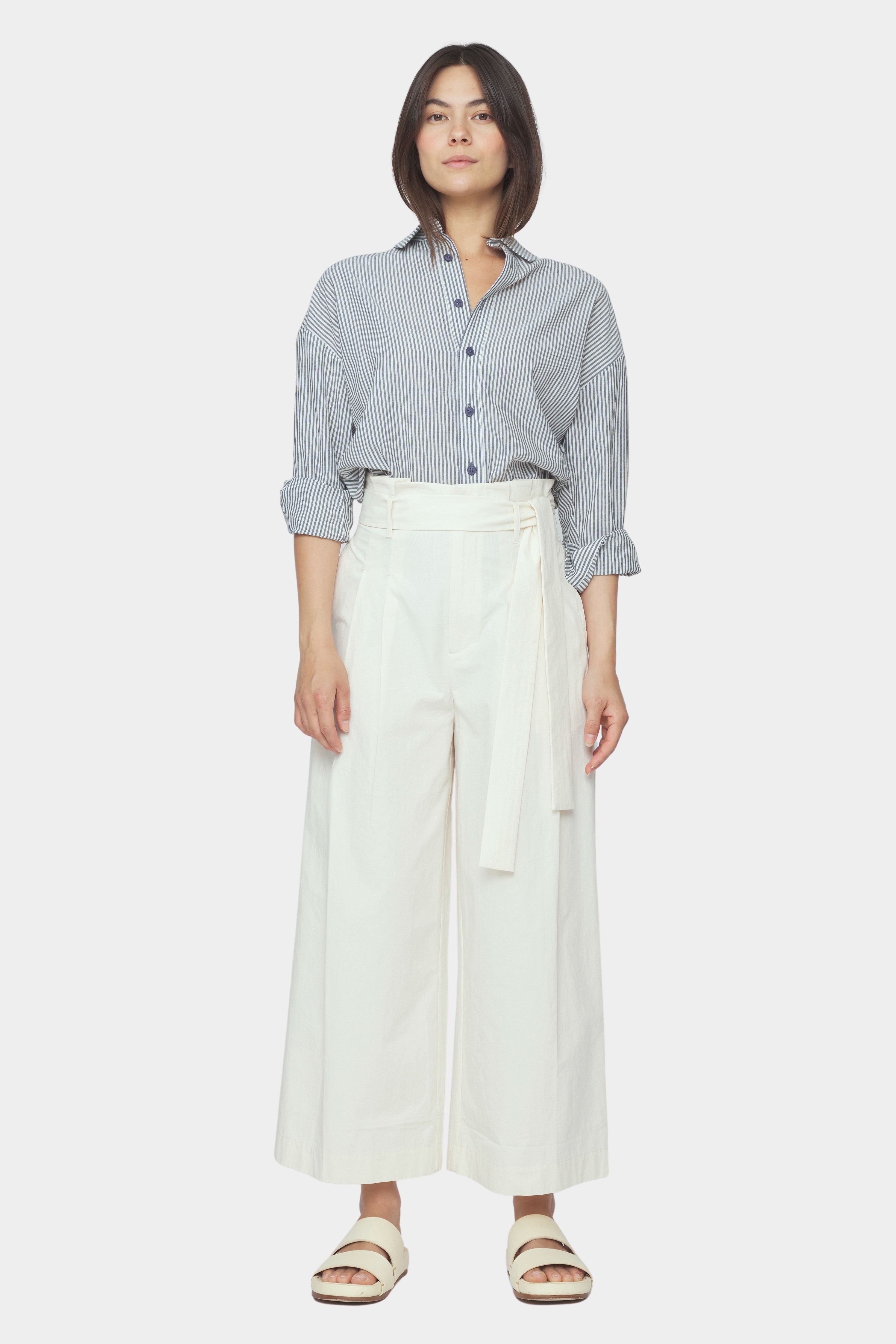 Front view of navy striped dolman shirt tucked into ivory wide leg trousers with rolled sleeves and button front