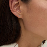 Model wearing delicate gold gemstone stud earrings styled for everyday layering.