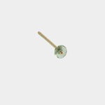 Close-up of gold stud earring with green gemstone detail on neutral background.