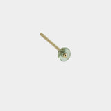 Close-up of gold stud earring with green gemstone detail on neutral background.