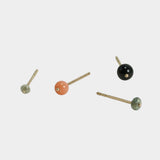 Minimalist gold stud earrings with multicolor gemstone accents on neutral background.
