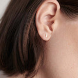 Model wearing 14K gold T-bar stud earring styled for everyday wear.