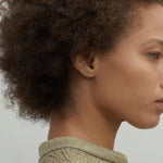 Model wearing delicate 14K gold long bar stud earring.