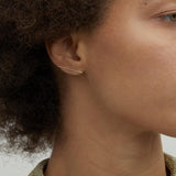 Model wearing 14K gold minimalist bar stud earrings.