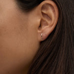 Model wearing delicate 14K gold curved bar stud earring.