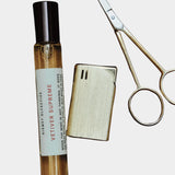 Kismet Olfactive Vetiver Supreme eau de parfum 10ml travel spray with cap removed next to metal scissors on neutral background
