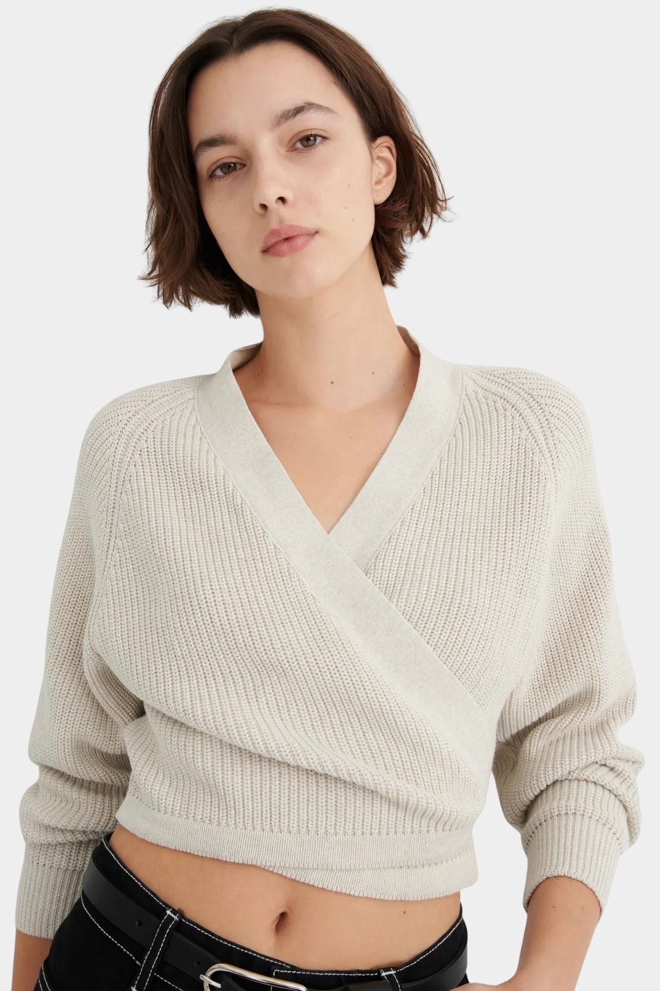 Three-quarter front view of the Oatmeal Kowtow Composure Cardigan styled with black trousers.