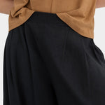 Close view of the black Kowtow Drape Pant showing the ribbed waistband and front pleats.