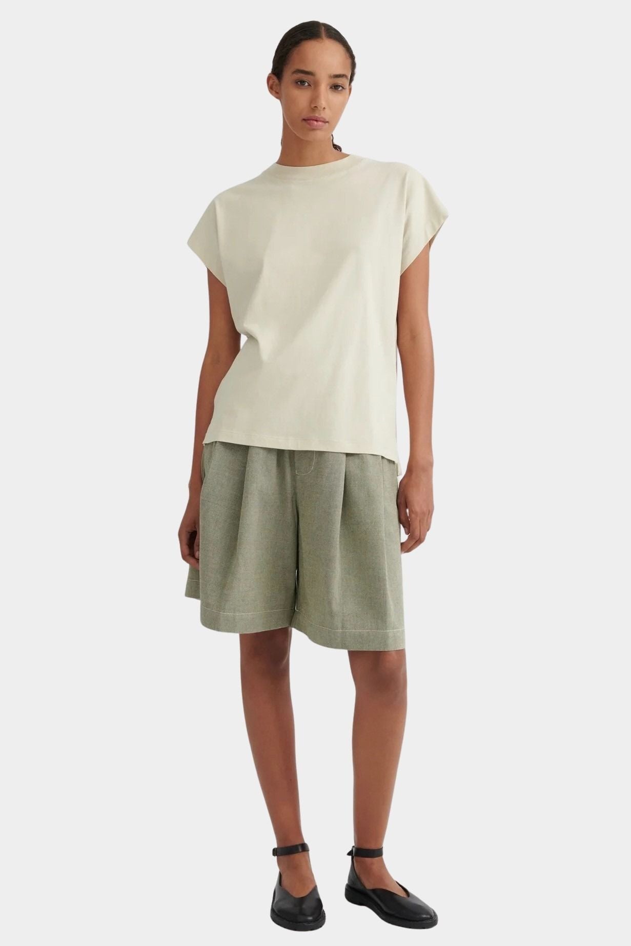 Model wearing the Stone Kowtow Geometry Tee with sage shorts and black Mary Janes at YUCCA Denver
