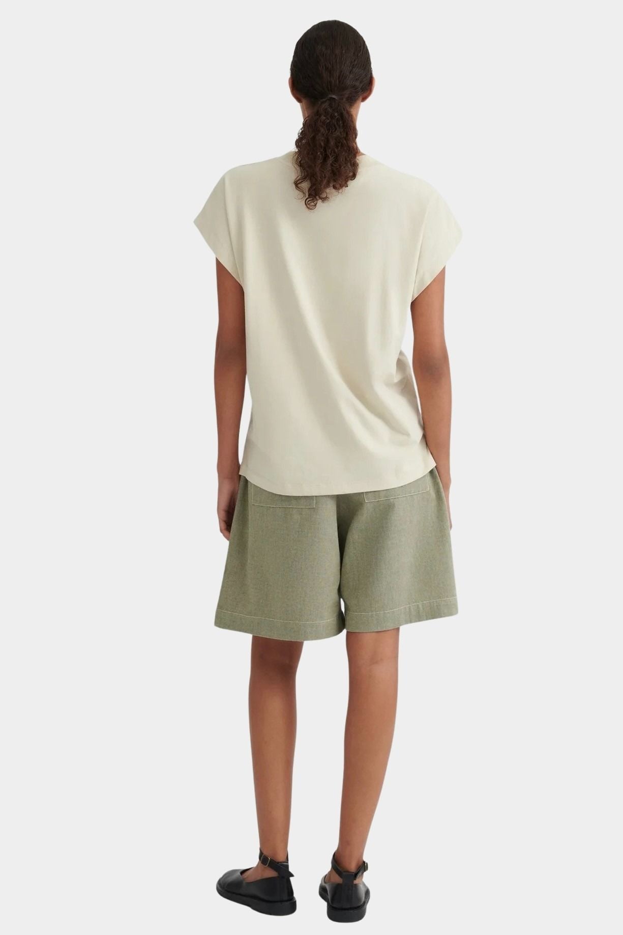 Back view of the Stone Kowtow Geometry Tee worn with sage shorts