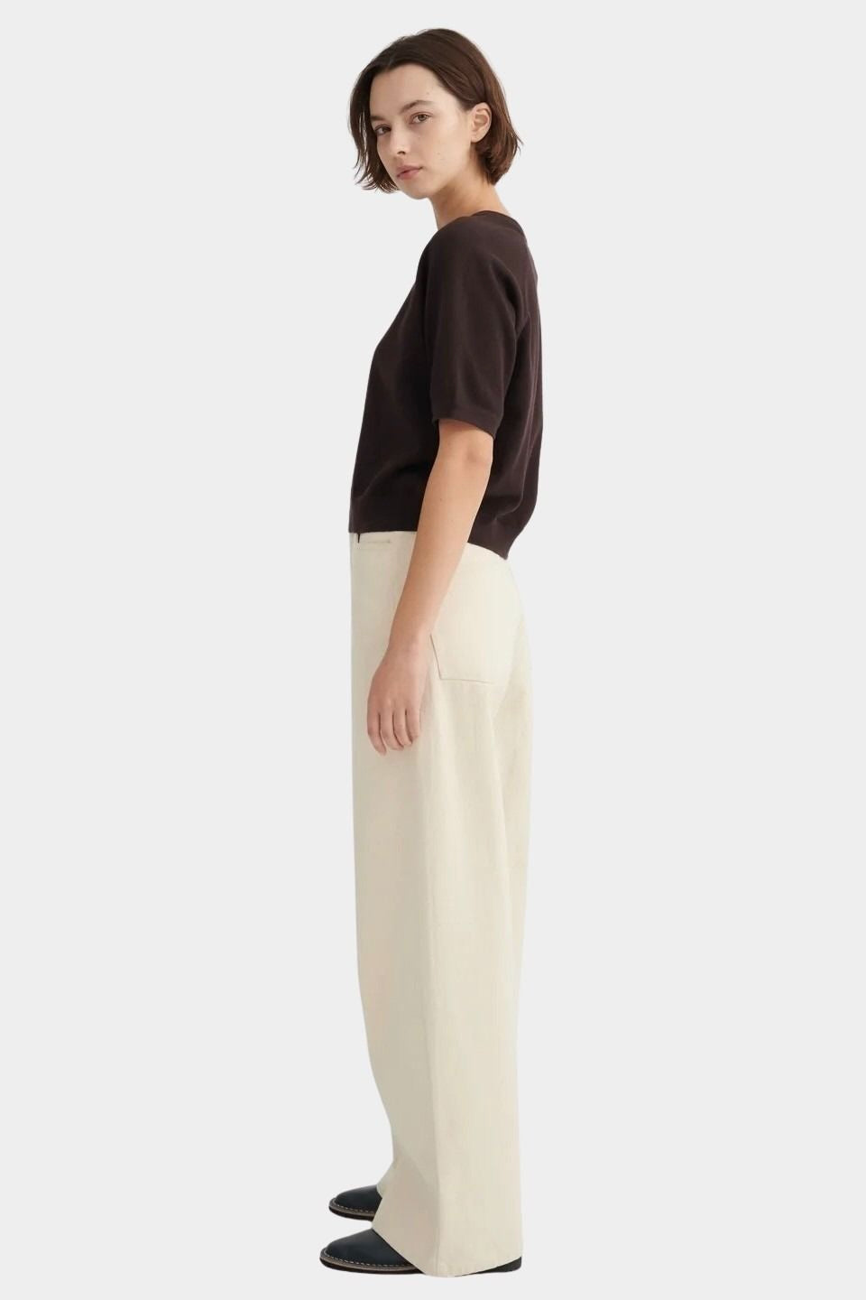 Side view of the Sable Shoreline Tee worn with wide cream trousers