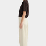 Side view of the Sable Shoreline Tee worn with wide cream trousers