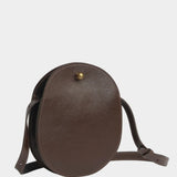 Angled view of the Chaga Eggi bag showing its rounded leather body, side gusset, and adjustable strap