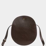 Chaga Eggi bag standing upright with its adjustable strap arranged around the base and brass closure visible
