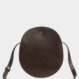 Chaga Eggi bag standing upright with its adjustable strap arranged around the base and brass closure visible