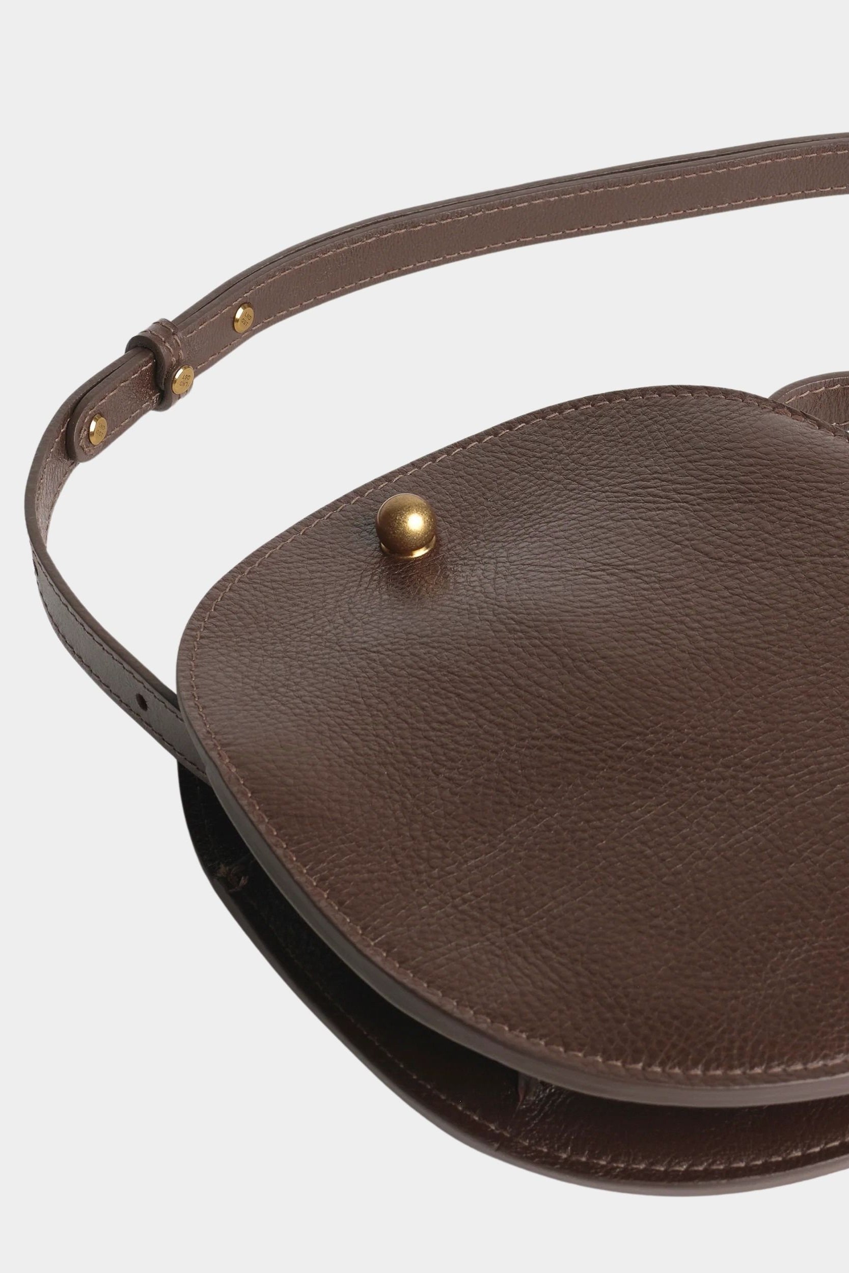 Chaga Eggi leather bag laid flat, showing its curved profile, gusset, and adjustable shoulder strap