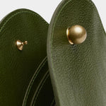 Close view of the Olive Eggi bag’s spherical brass closure, pebbled leather, and interior dividers
