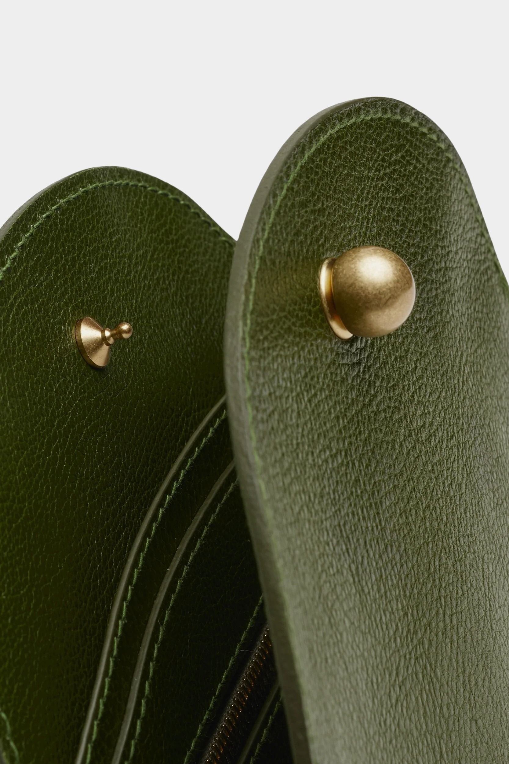 Close view of the Olive Eggi bag’s spherical brass closure, pebbled leather, and interior dividers