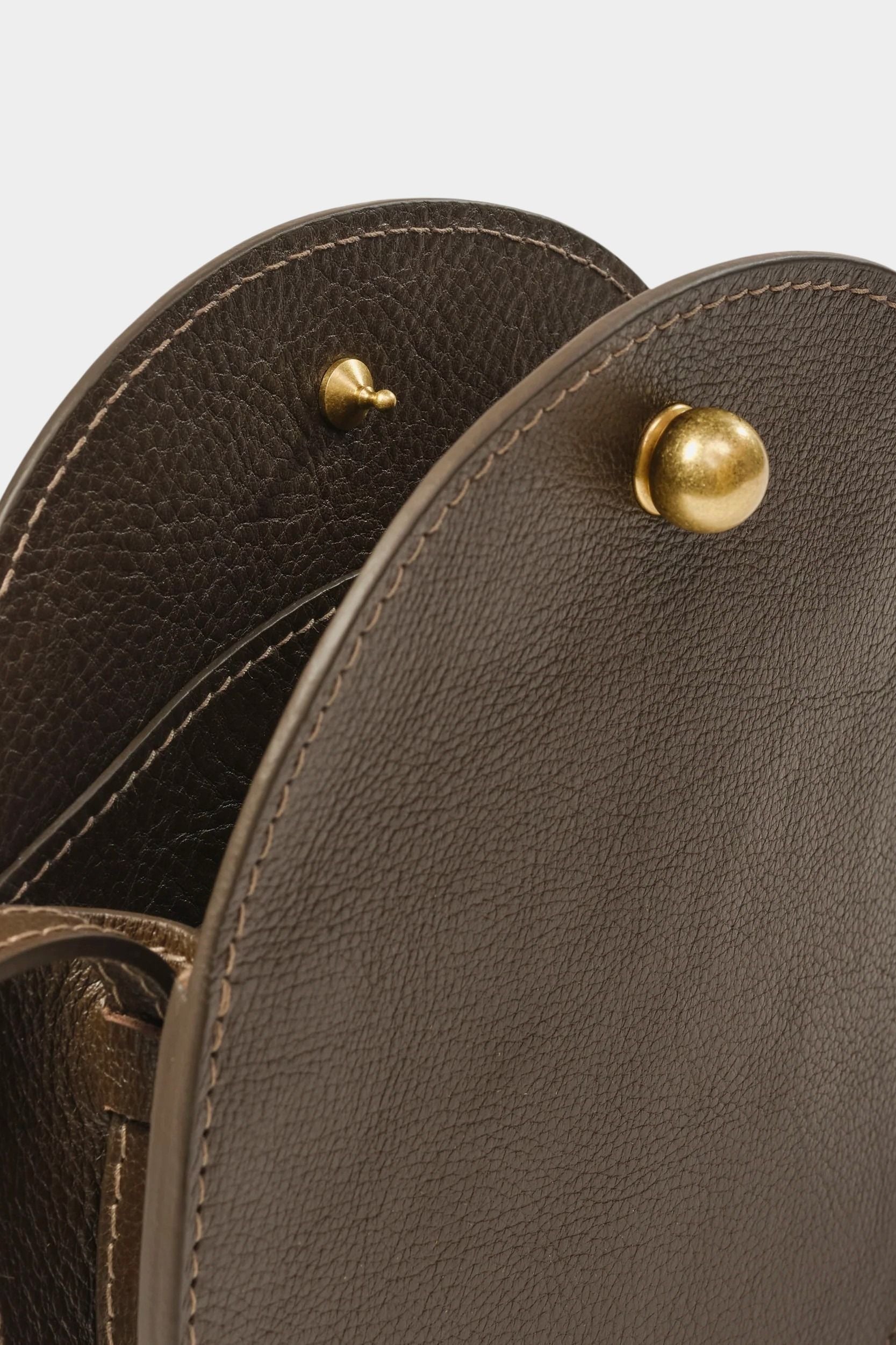 Close view of the Mini Eggi bag’s spherical brass closure and pebbled Chaga leather