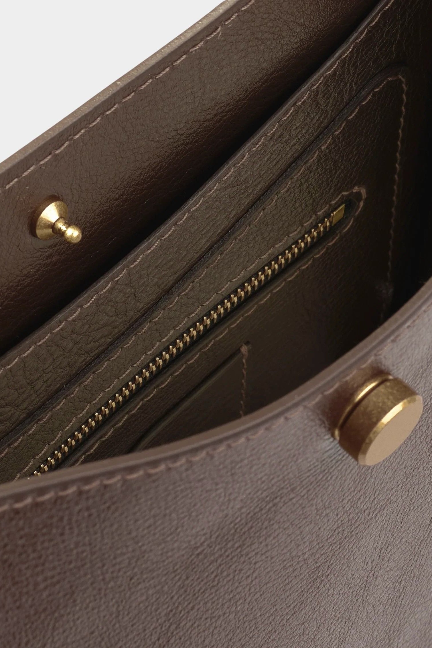Close view of the Chaga Savoie bag’s interior zippered pocket, pebbled leather, and brass closure
