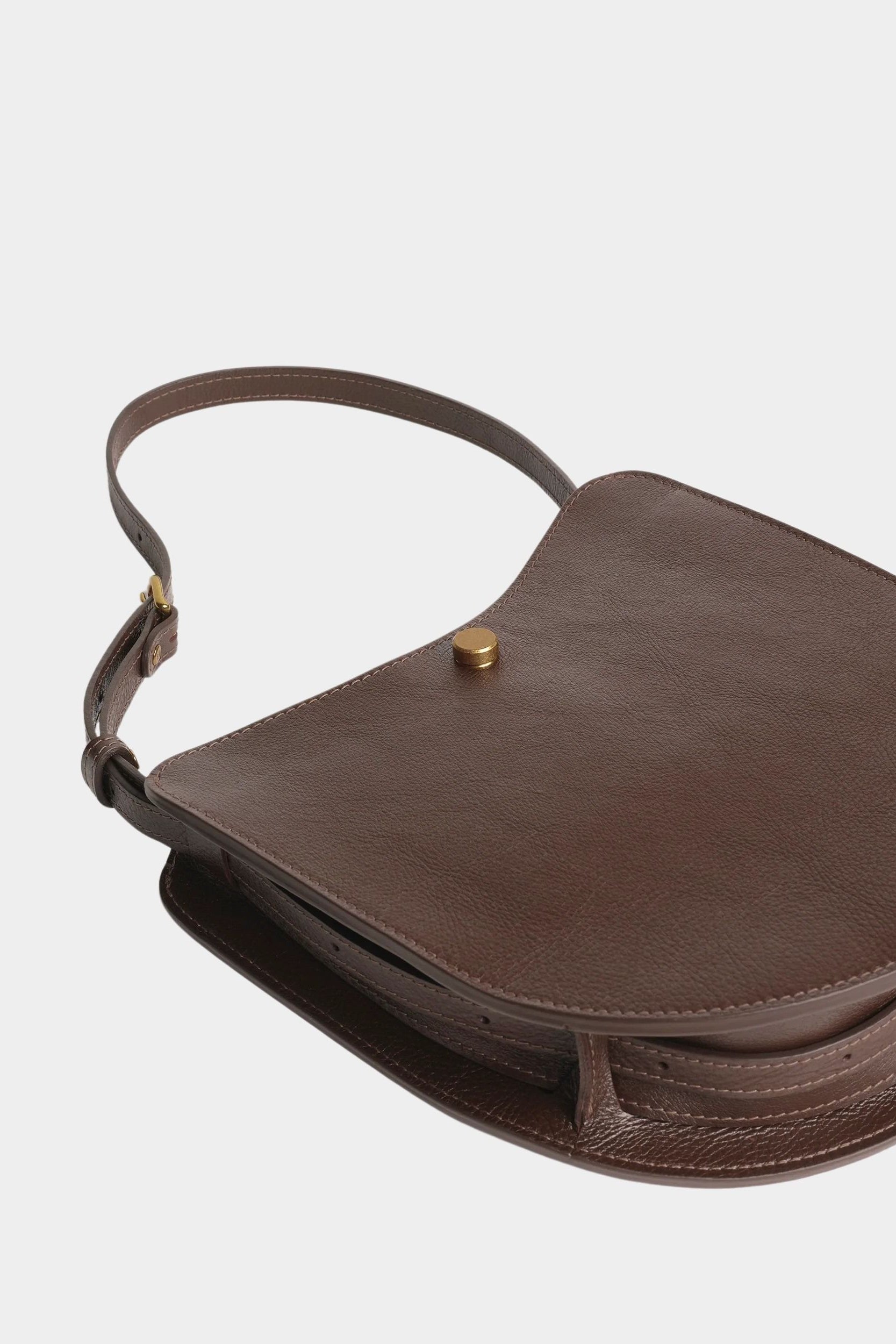 Chaga Savoie bag laid flat, showing its curved leather body, divided interior, and shoulder strap
