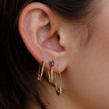 Loren Stewart Cirque Safety Pin Earring with blue sapphire worn in a layered gold ear stack