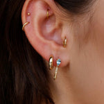 Model wearing 14K gold diamond and blue topaz drop hoop earrings.