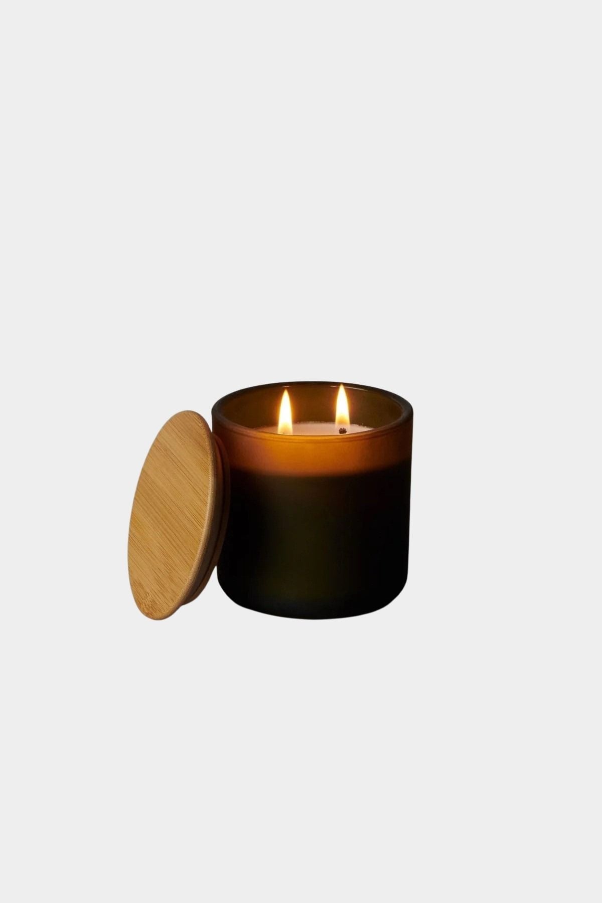 Los Poblanos Vela del Bosque Candle with dark frosted glass vessel, bamboo lid, and double wick candle burning