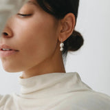 Maslo Jewelry double orb sterling silver drop earrings worn on model with neutral top, close-up side profile