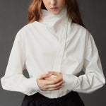 Close detail of the Mijeong Park white cotton shirt showing its asymmetric collar and button placket