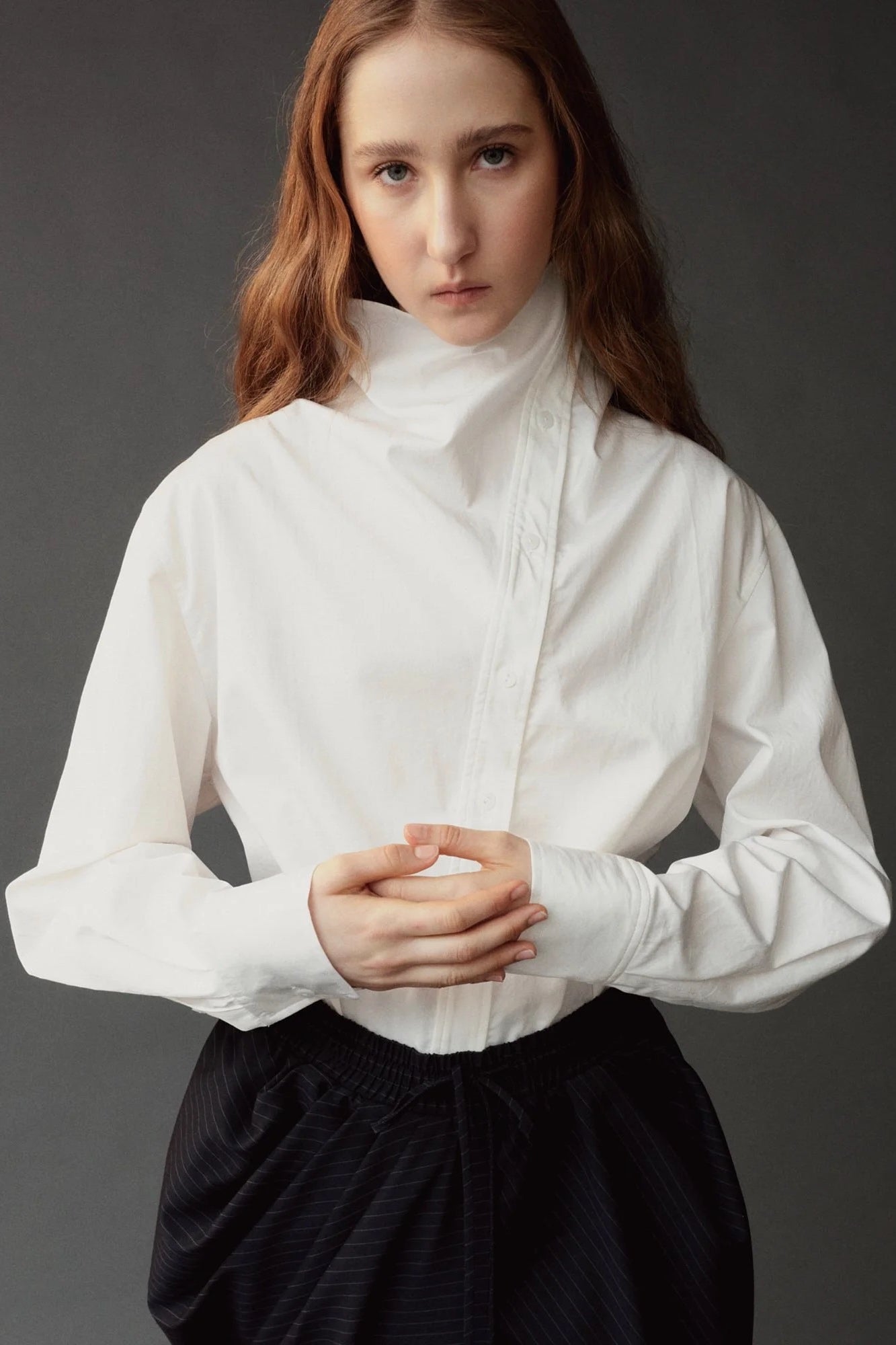 Close detail of the Mijeong Park white cotton shirt showing its asymmetric collar and button placket