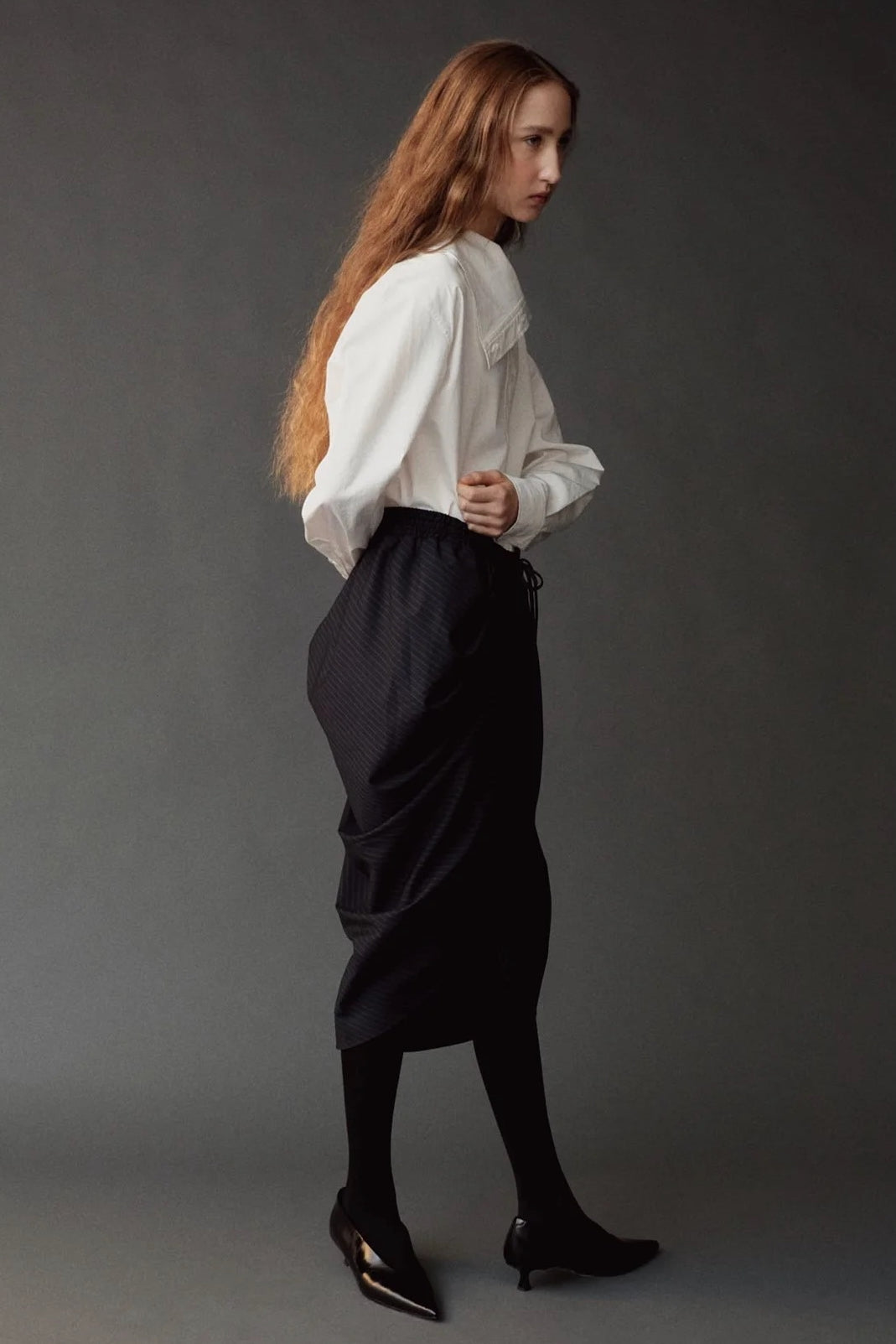 Side view of the Mijeong Park white cotton shirt styled with a sculptural black skirt