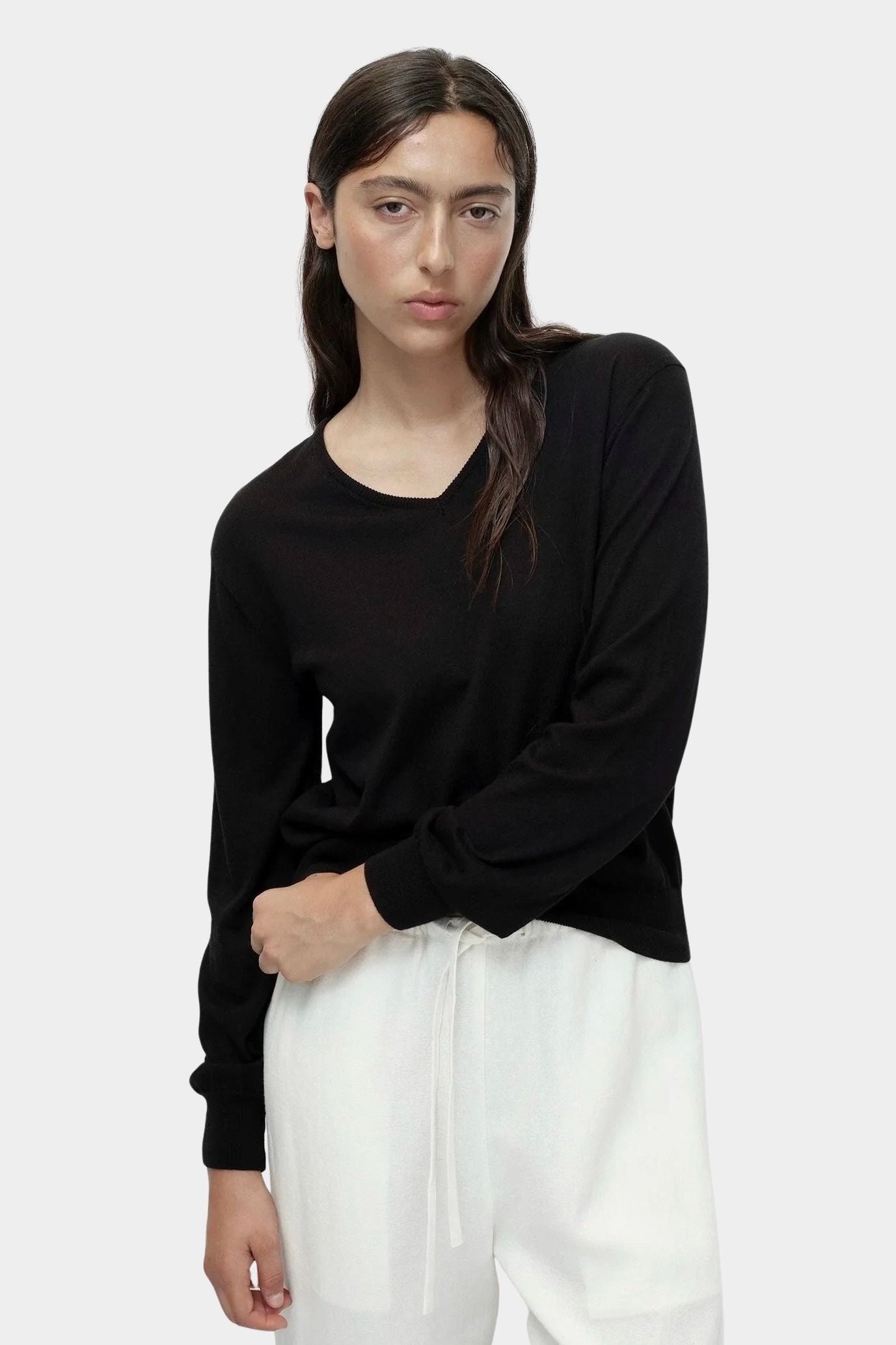 Cotton blend v neck knit top in black by Mijeong Park styled with white wide leg pants