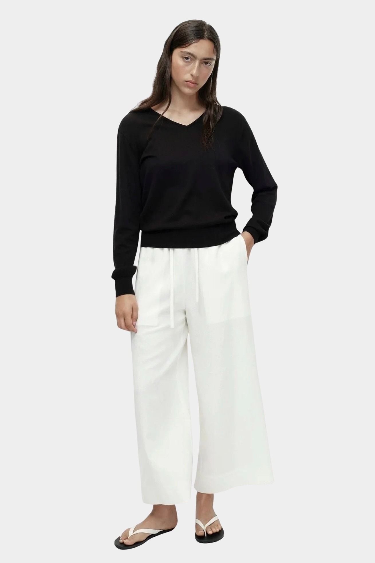 Cotton blend v neck knit top in black by Mijeong Park styled with white wide leg pants