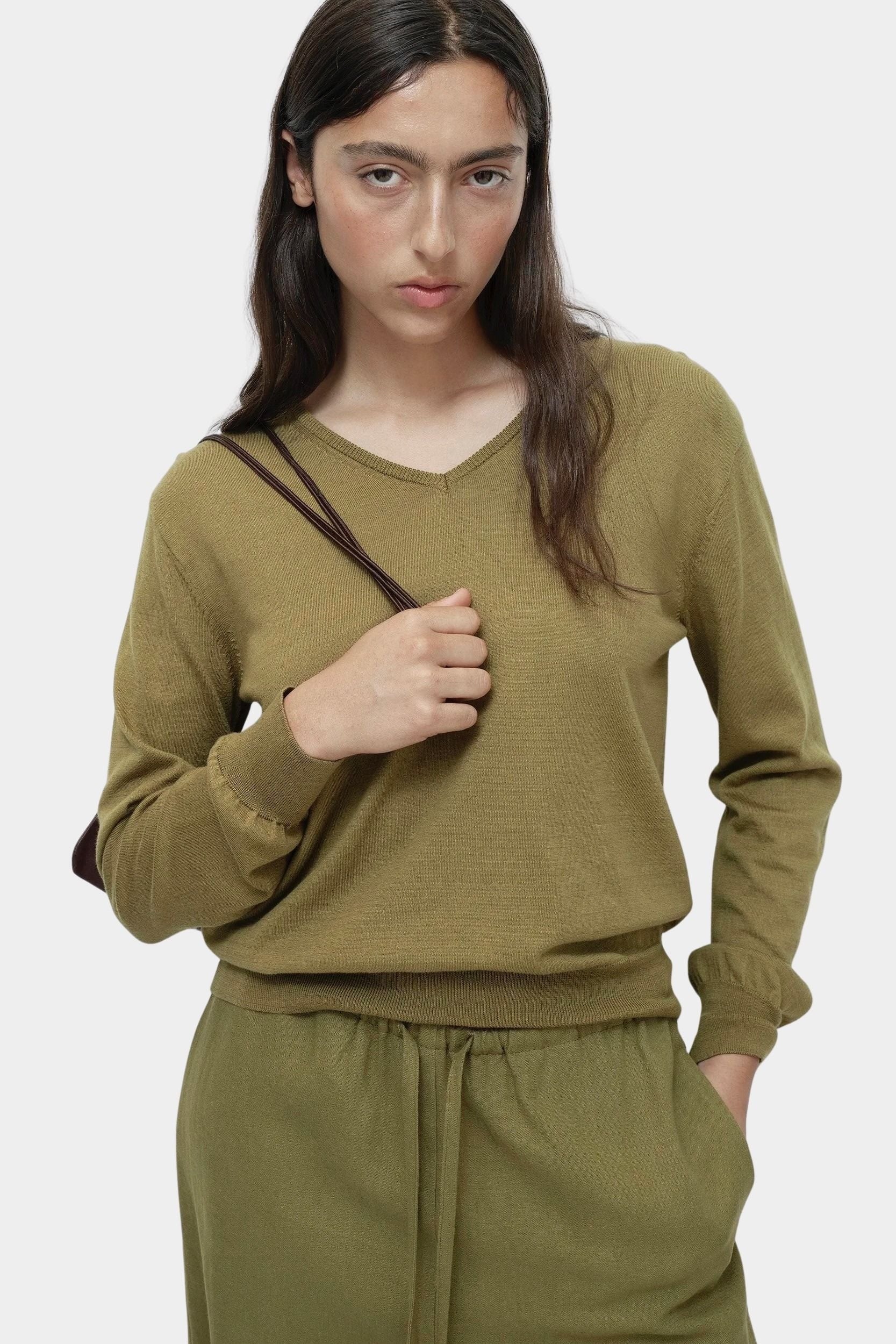 Green cotton blend v neck knit top by Mijeong Park with relaxed fit styled with matching knit pants