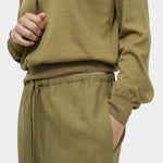 Close-up of green cotton blend v neck knit top by Mijeong Park with rib hem and drawstring knit pants