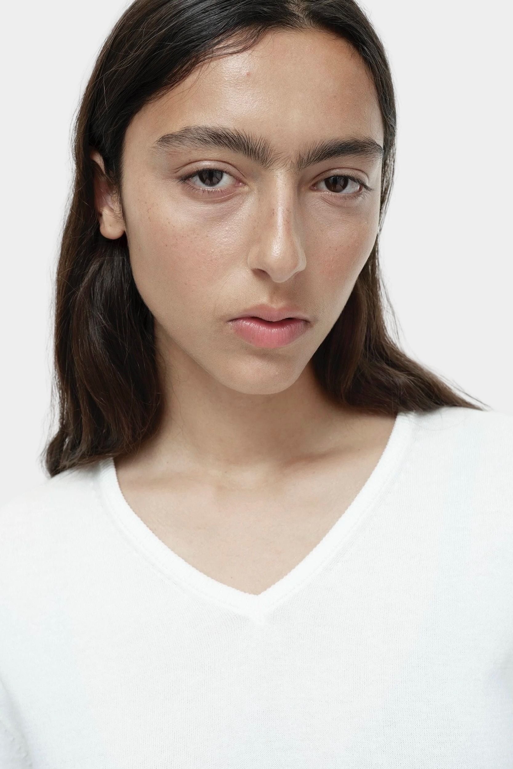 Close-up of white cotton blend v neck knit top by Mijeong Park showing v neckline and knit texture