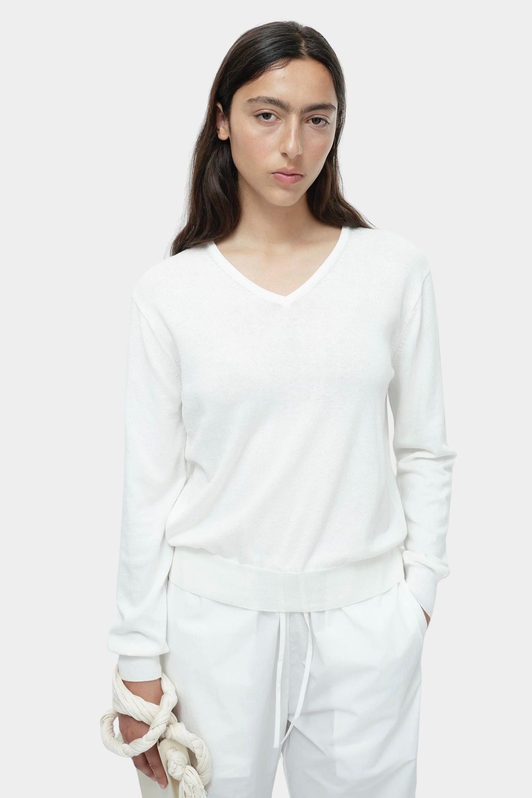 White cotton blend v neck knit top by Mijeong Park with rib hem and relaxed silhouette