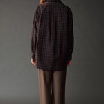 Back view of the Mijeong Park Oversized Plaid Shirt in black plaid showing the center pleat and curved hem