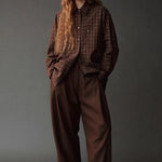 Model wearing the Mijeong Park Oversized Plaid Shirt in brown plaid with relaxed brown trousers