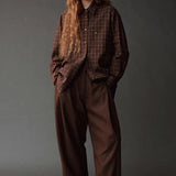 Model wearing the Mijeong Park Oversized Plaid Shirt in brown plaid with relaxed brown trousers